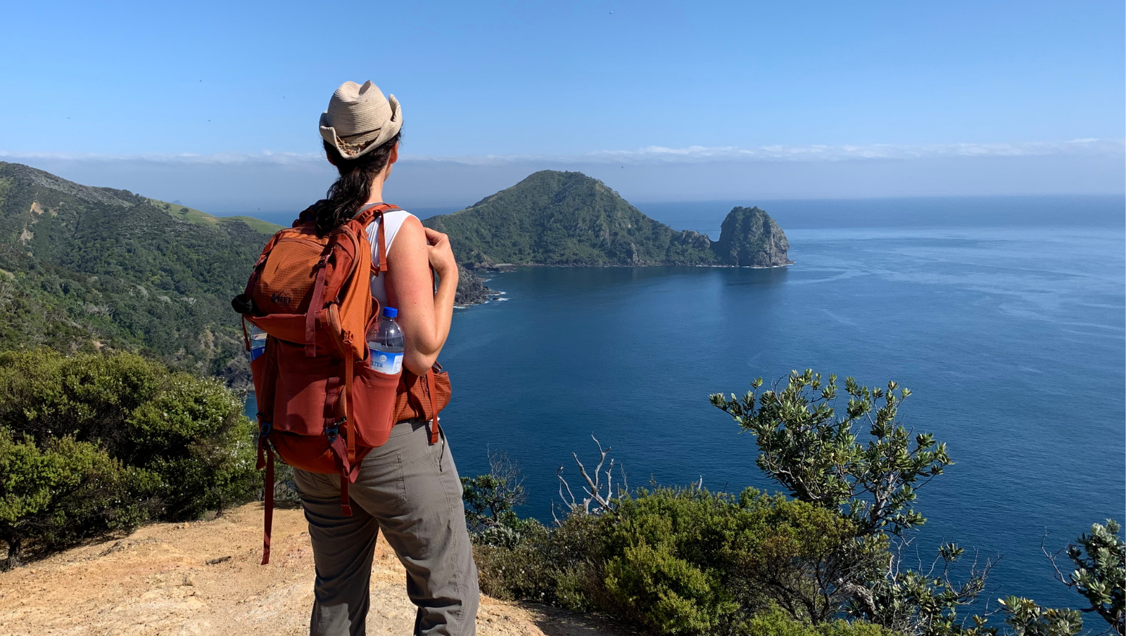 Jen hiking a remote trail with coastline views
